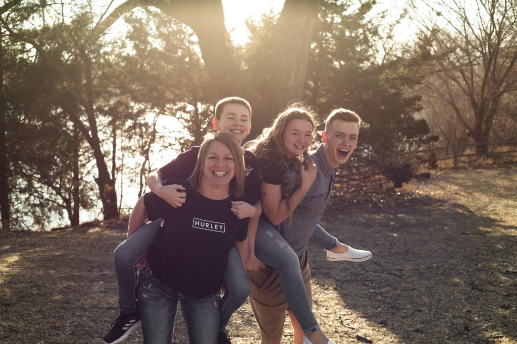 Mom and brother giving younger kids a piggy back ride and laughing