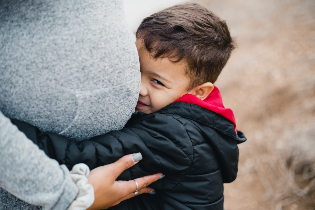 Son hugging mom's pregnant belly and smiling