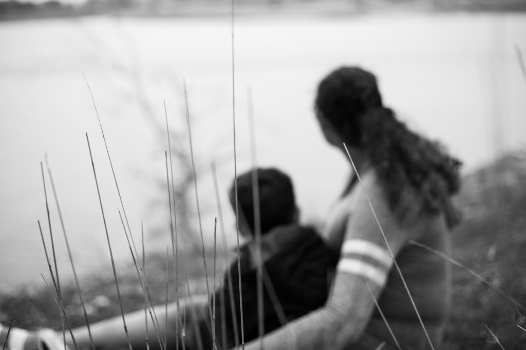 Black and white image of mother and son looking off at the lake