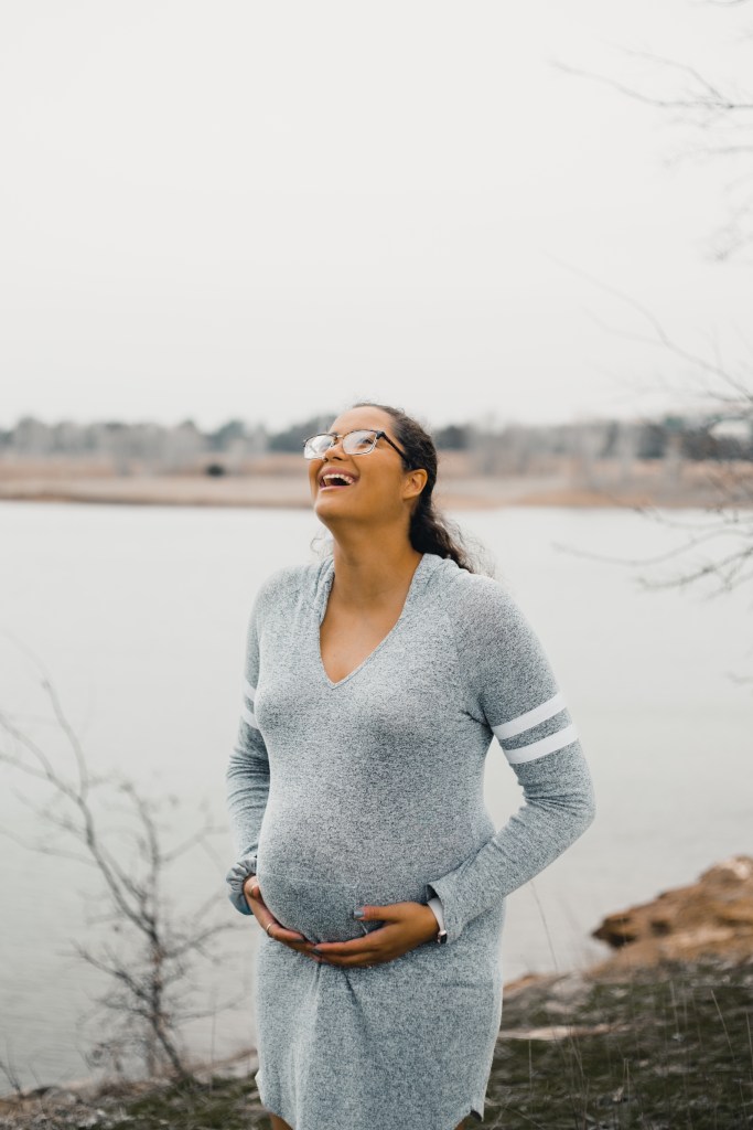 Smiling expectant mother in front of lake during maternity photography session